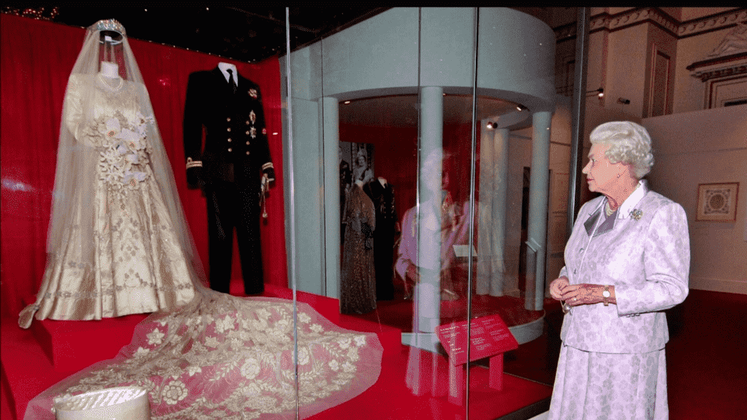 Queen Elizabeth looks at her brocade wedding dress at the Museum of London